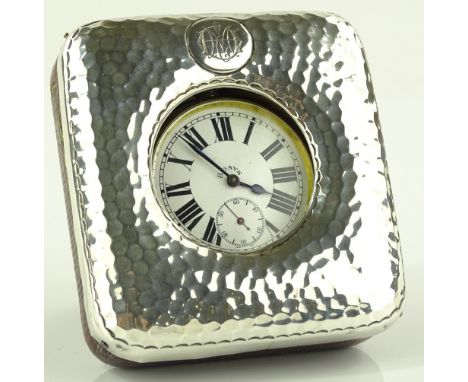 An unmarked white metal fronted 8-day travelling clock, red leather case with stand, height 96mm, working order.