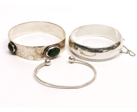 A silver and nephrite jade bangle and two others.