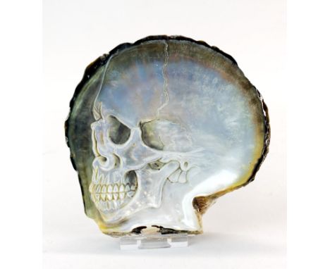 A hand carved black lip oyster mother of pearl shell with skull, with perspex display stand.