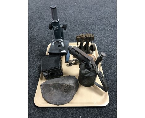 A tray containing a vintage blowtorch, live steam engine component, a Canco microscope, a fossilized husk, Brownie camera, et