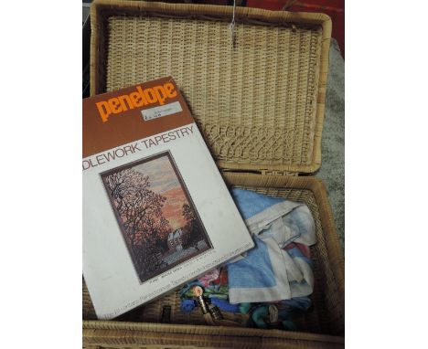 A wicker hamper containing tapestry wools, scissors and embroidery threads and a vintage Ulster tea towel.