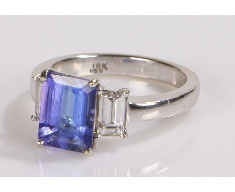 18 carat white gold tanzanite and diamond set ring, the central tanzanite at 2.71ct flanked by a baguette cut diamond to eith