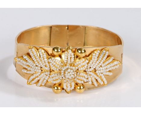 Yellow metal pearl set bangle, with applied seed pearls to form a flower head and long leaves, 65mm diameter, 23 grams
