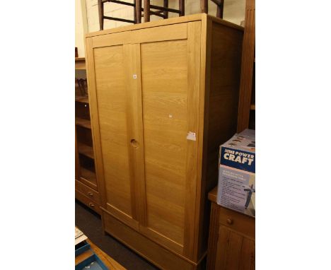 Ercol contemporary light oak wardrobe having two doors above a base drawer, 199cm high by 115cm wide by 62cm deep.