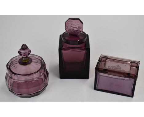 Three pieces of amethyst glass comprising a Heinrich Hoffman lidded box and scent bottle both with intaglio decoration and a 