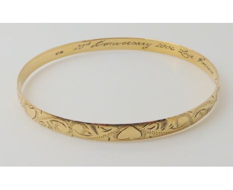 A 9ct gold engraved bangle, diameter 6.8cm, width 0.6cm, inscribed to the interior, weight 12.4gms Condition Report: Availabl