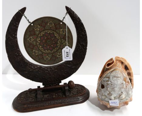 An Indian carved wooden and brass table gong and a carved cameo shell light shade Condition Report: shade has a hole in it. 