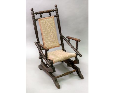 A child's late Victorian walnut ring turned frame rocking chair, with upholstered back panel and seat.