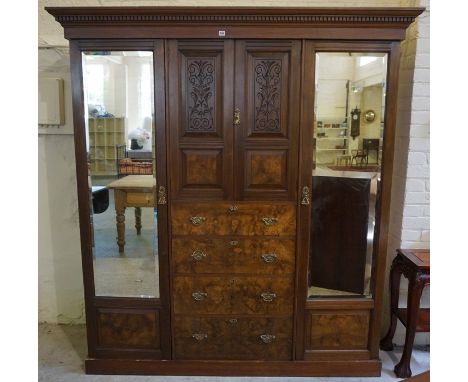 A Late Victorian Walnut Wardrobe, Having two cupboard doors above four drawers, flanked with a mirrored door, enclosing a han