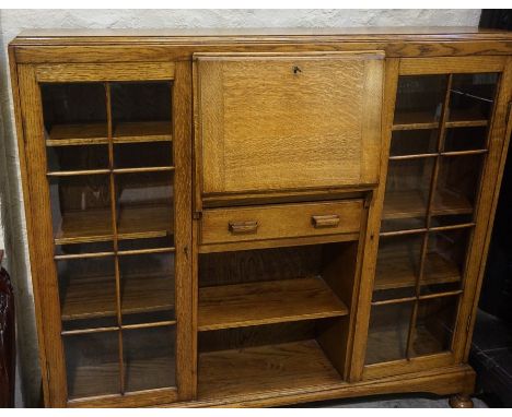 An Oak Secretaire Display Cabinet, circa 1930s, Having a fall front enclosing pigeon holes, flanked with a glazed door enclos