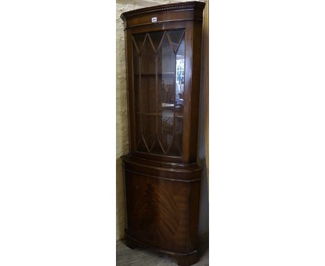 A Reproduction Corner Cabinet, Having a glazed door enclosing a shelved interior, above a cupboard door, 180cm high, 60cm wid