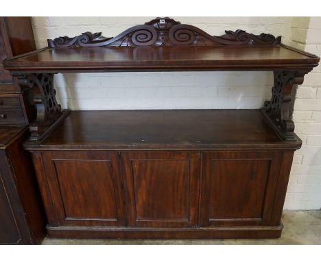 A Victorian Mahogany Buffet Cabinet, Having a rectangular top, raised on carved supports, above an open recess and three cupb