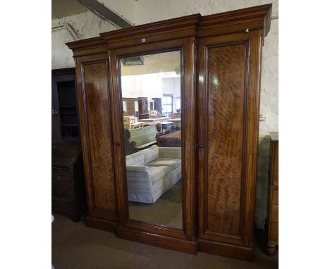 A Victorian Mahogany Breakfront Three Door Wardrobe, Having a moulded cornice above a mirrored door, enclosing assorted drawe