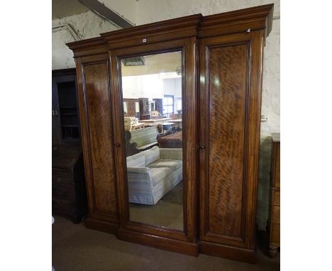 A Victorian Mahogany Breakfront Three Door Wardrobe, Having a moulded cornice above a mirrored door, enclosing assorted drawe