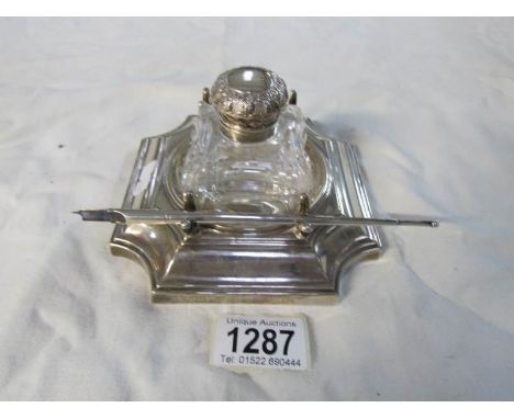 A silver ink stand with glass inkwell and silver dip pen