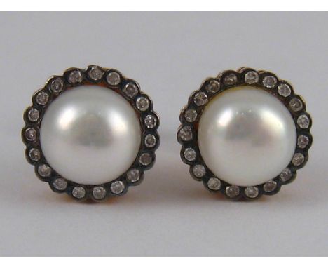 A pair of gilt metal (tests silver) cultured pearl and diamond ear studs, pearls approx 9mm diameter, fittings marked 585.

