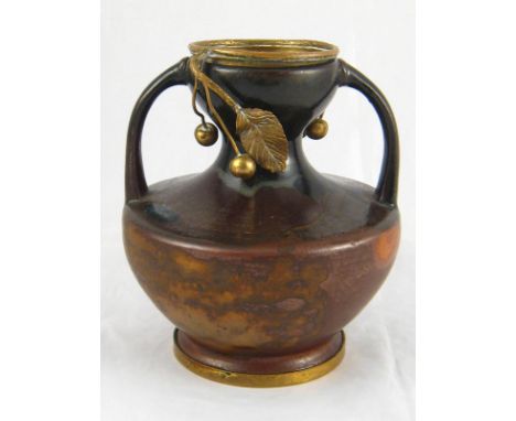 A French ceramic two handled studio vase with brown flambe glaze and gilt metal cherries dependent from the rim, the base sta