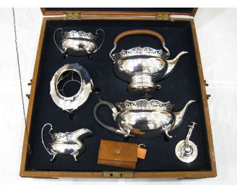 A tea set of oval bellied form with broad pierced rims comprising teapot, kettle on burner stand, cream jug and sugar basin b