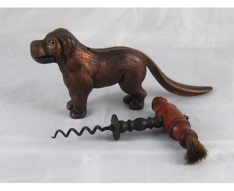 An antique corkscrew with brush and friction disc and a cast iron dog nut cracker.