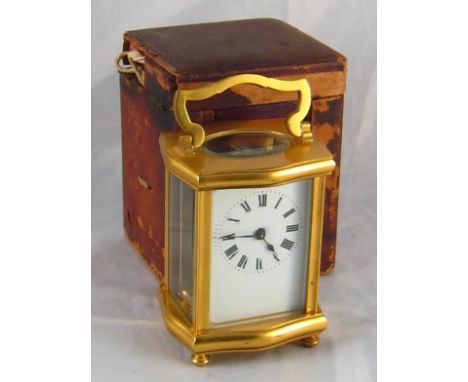 A gilt brass clock in original travelling box , case AF, the clock with shaped case, oval top window and white enamel face. M