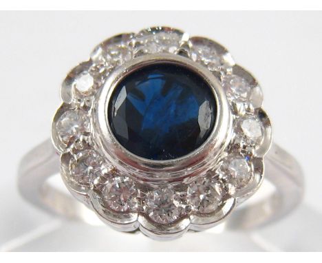 A white metal (tests 18 carat gold) sapphire and diamond ring, the sapphire measuring approx 6mm diameter, estimated total di