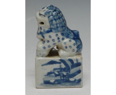 A Chinese porcelain seal, modelled with a seated guardian lion, its rectangular pedestal inscribed recto and verso in undergl