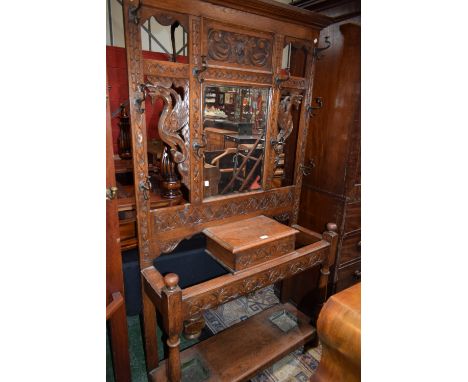 A 20th century carved oak hallstand, outswept cornice above a central bevelled plate mirror, an arrangement of hooks and walk