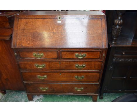 A 19th century oak bureau, of large proportions, fall front enclosing a small central door, small drawers and pigeon holes ab