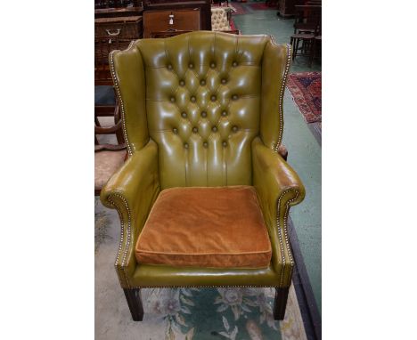 A 20th century Chesterfield type wingback armchair, deep button back, scroll arms, 112cm high