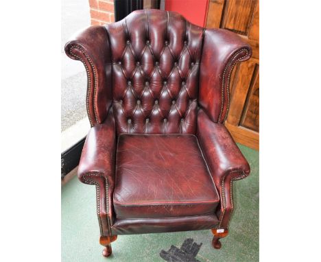 A 20th century leather Chesterfield type reception wingback armchair, scroll arm, deep button back, cabriole legs, pad feet, 