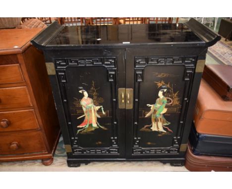 An Oriental lacquered style side cabinet, rectangular pagoda top above a pair of doors enclosing a fitted interior, each door