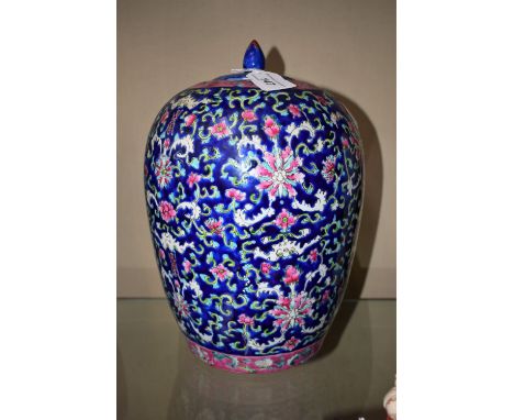 A Chinese ovoid jar and cover, brightly painted in polychrome with flowers and scrolling leaves, on a blue ground, bud finial