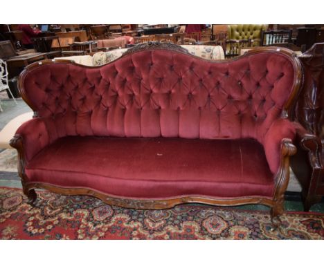 A Victorian mahogany framed wingback salon sofa, serpentine cresting rail carved and applied with flowerheads and foliage, th