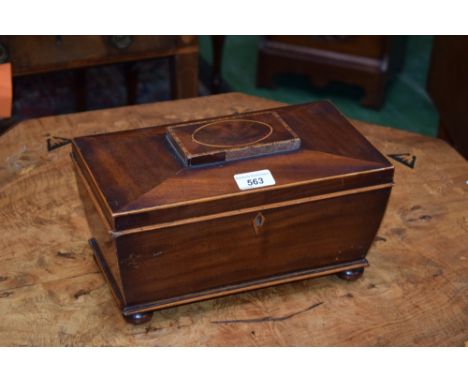 A George IV mahogany sarcophagus tea caddy, pylon-shaped hinged cover centred by a tablet inlaid with barber pole stringing, 