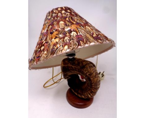 A ram's horn table lamp on a circular wooden base together with a bird feather shade