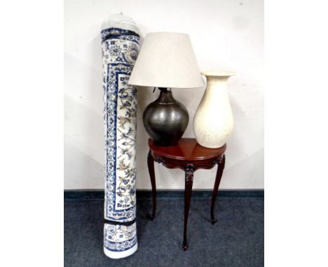 A Next woolen rug together with a demi-lune hall table in a mahogany finish, a metal table lamp with shade and a pottery vase