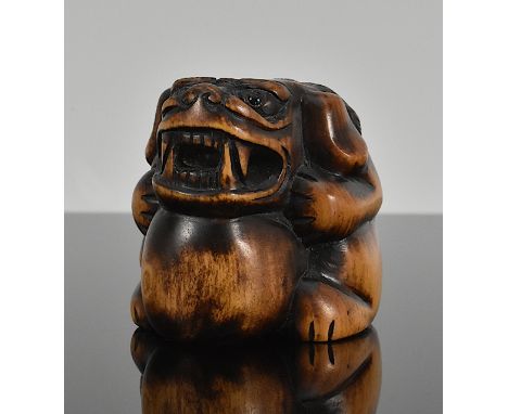 Netsuke. Shishi stützt den Kopf auf einen Ball. Eingelegte Augen. Sign. Buchsbaum. Japan. Frühes 19. Jh. L 4 cm.