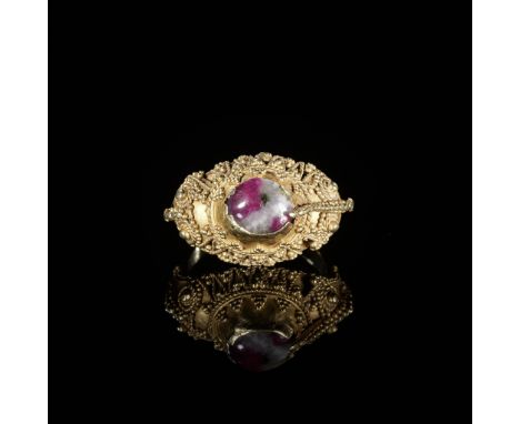 A CORUNDUM-SET GOLD 'FLOWERS AND BIRD' PRIEST'S RINGIndonesia, Bali, 19th to early 20th century. The gold ring with a conical