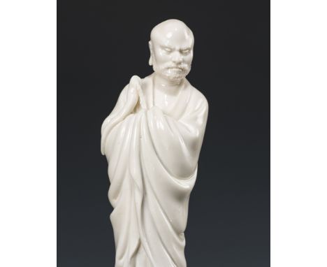 A DEHUA FIGURE OF DAMO (BODHIDHARMA), CHINA, 17TH-18TH CENTURY 十七至十八世紀德化窯白釉達摩像Finely modeled standing barefoot, shrouded in a