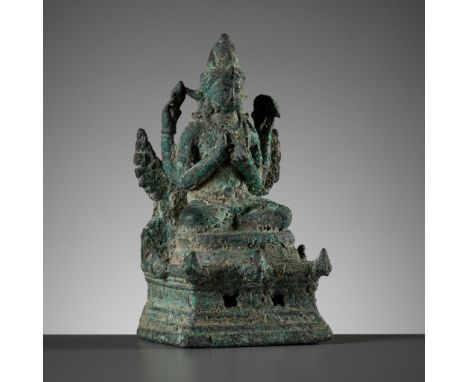 A BRONZE FIGURE OF AVALOKITESHVARA SADAKSARI, JAVA9th-10th century. The four-armed deity seated in dhyanasana atop a lotus th