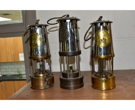 THREE BRASS AND STEEL MINER'S LAMPS, comprising an E Thomas &amp; Williams Ltd Cambrian lamp, no 18149, and two The Protector