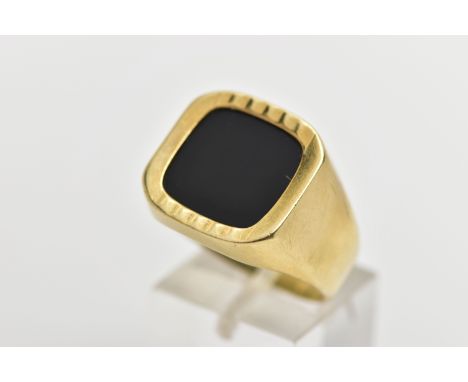 AN ONYX SIGNET RING, the square shape onyx panel, within a part textured and polished surround, to the tapered band, stamped 