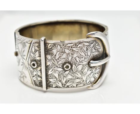 A WHITE METAL HINGED BANGLE, wide bangle approximate width 30.3mm, in the form of a belt and buckle with engraved ivy leaf de