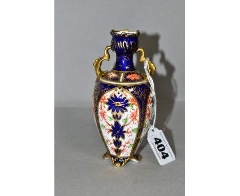 A ROYAL CROWN DERBY OLD IMARI 1128 TWIN HANDLED VASE, of baluster form with gilt foliate handles, standing on four foliate fe