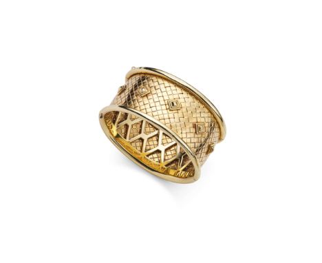 Garrard: A wide cuff bangle, circa 1980  Of interwoven design, accented by tiered rivets to the front, within a tubular fram