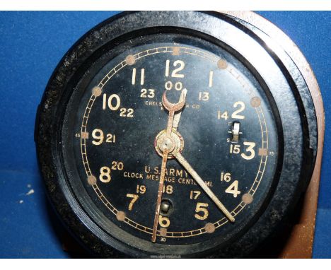 A cased bulkhead mounting clock having a clockwork movement. The black face having Arabic numerals for the 12 and 24 hour sys