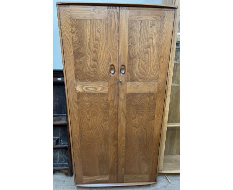 An Ercol light elm two door wardrobe, with panelled doors enclosing hanging space, 91cm wide x 183cm high 