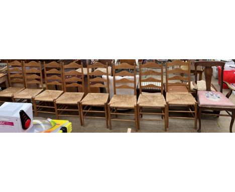 A set of eight early 20th century oak ladder back dining chairs with rush seats on tapering legs together with an oak elbow c