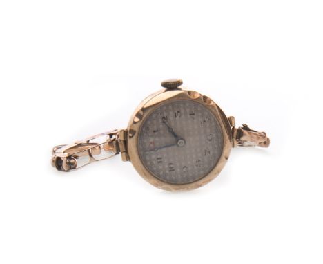 LADY'S EARLY TWENTIETH CENTURY NINE CARAT GOLD MANUAL WIND WRIST WATCH, the round machined dial with Arabic numerals in black