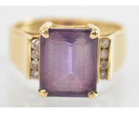 A 14ct yellow gold amethyst and diamond set ring, the central square cut amethyst approx 3ct, flanked by eight small diamonds